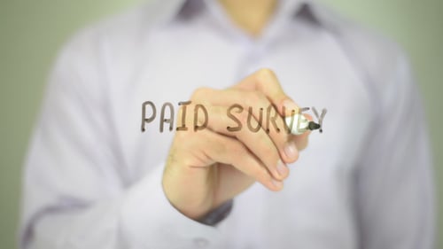 Hand Writes "Paid Survey" on Clear Surface