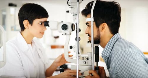 Optometrist Examines Man's Eyes with Ophthalmic Refractor