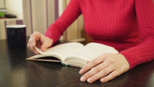 Adult Reading Book at Table, Close Up Shot