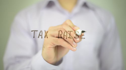 Person Writes Tax Raise on Transparent Surface