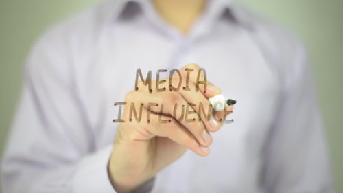 Person Writes Media Influence on Clear Surface