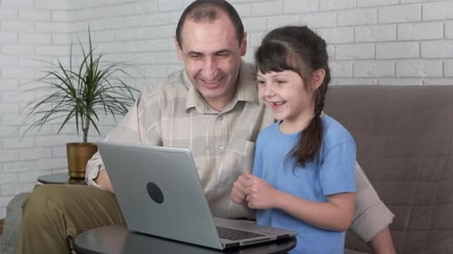 Adult and Child Looking at Laptop Together