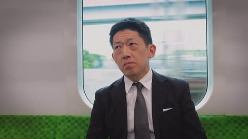 Japanischer Geschäftsmann steigt in einem Zug auf