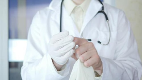 Medical Professional Putting on Gloves in Hospital Setting