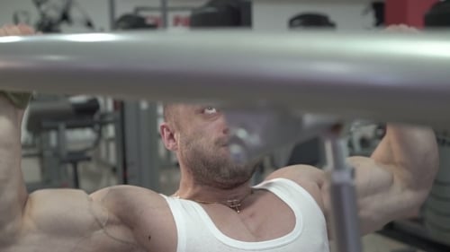 Muscular Man Lifts Weights at the Gym