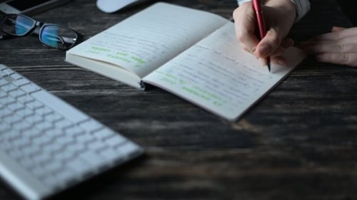 A Young Woman Writing While Sitting In Her Office At Night