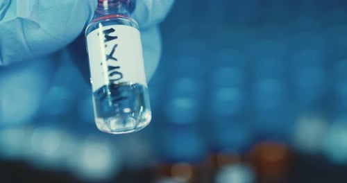 Gloved Hands Placing Clear Vial into Rack