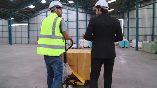 Factory Workers Deliver Boxes Package on a Pushing Trolley in the Warehouse