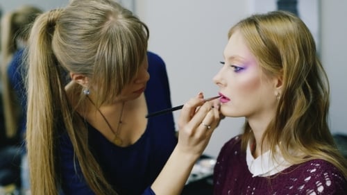 Von einer Frau, die Lippenstift auf den Lippen schminkt