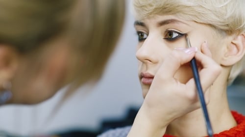 Applying Black Eyeliner on Young Woman's Eye