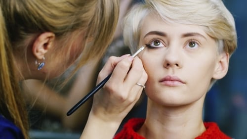 Makeup Artist Applying Eyeliner to Young Woman