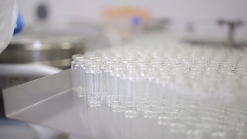 Gloved Hand Arranges Vials in Pharmaceutical Lab