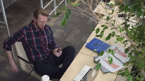 Man at Desk Using Mobile Phone in Office