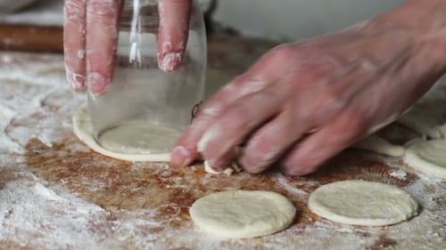 Hands Cutting Dough Into Circles With Glass