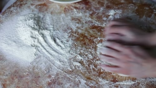 Hands Kneading Dough on Floured Surface
