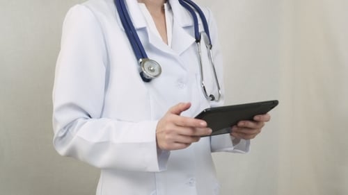 Der Arzt im weißen Kittel bei der Arbeit mit dem Tablet.