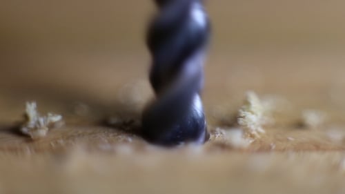 The Drill Bit is Drilling a Hole in Wood