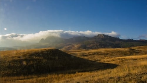 Landscape of Golden Grass Hills and Cloudy Mountains