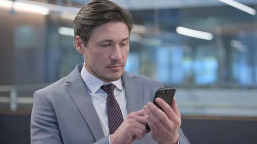Man in Suit Using Cell Phone Indoors