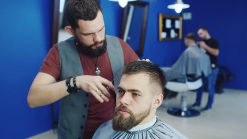 Barber schneidet die Haare des Kunden mit einer Haarschneidemaschine