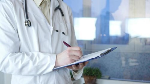 Doctor Writing on a Clipboard in Clinic