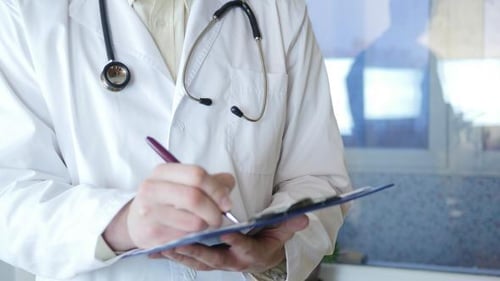 Doctor Writes on Clipboard in Hospital Close Up