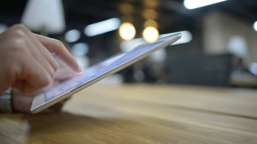 Fingers Tapping on Digital Tablet at Wooden Table