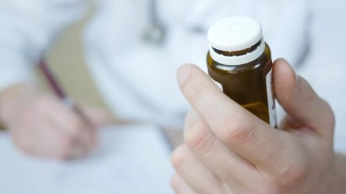 Doctor Holding Prescription Medicine Bottle in Clinic