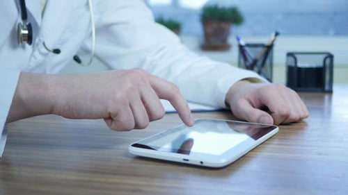 Arzt tippt SMS auf Tablet