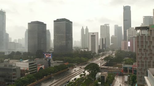 Aerial Dolly Shot fliegt an einem nassen Regentag in Jakarta über eine mehrspurige Straße in die Stadt