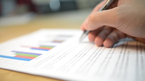 Hand Analyzing Business Report with Graph Using Pen
