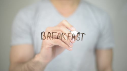 Man Writes Breakfast on Clear Surface with Marker