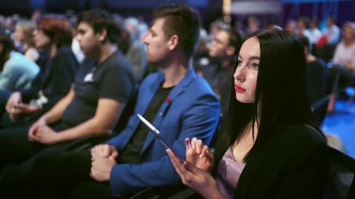 Audience Watching a Corporate Presentation With Woman Using Tablet