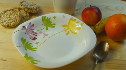 Pouring Yellow Corn Flakes into a Floral Bowl