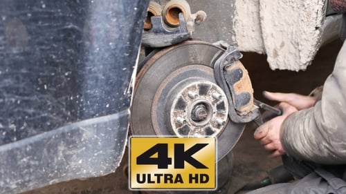 Auto Mechanic Working On Brakes In Car Repair Shop