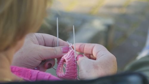 Woman Knitting Pink Yarn with Needles Close Up