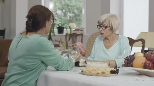 Dos mujeres mayores positivas viendo fotos en un álbum de fotos y hablando