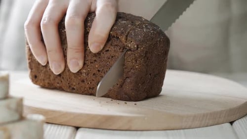 Closeup View of Slicing Bread on Wooden Cutting Board.