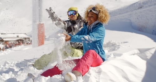 Jeune couple jouant dans la neige dans une station de ski