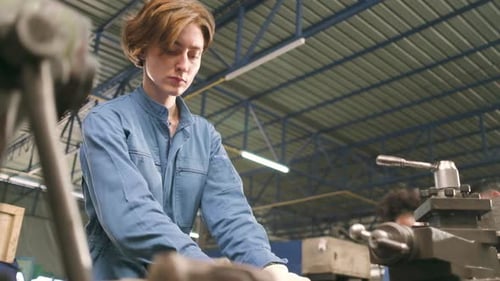 Professional young White female worker works in metalwork manufacturing factory.