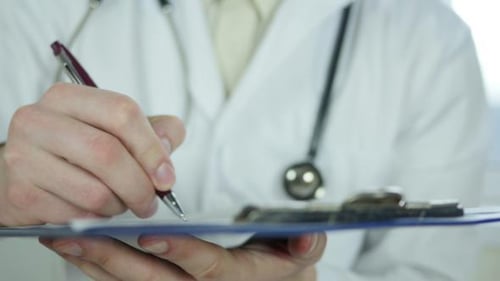 Doctor Writing on Clipboard in Hospital Close Up