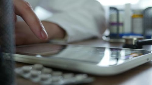Doctor Typing On Tablet In Office