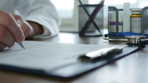 Doctor Writes on Form with Pen in Office
