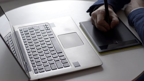 Man Using Stylus, Tablet, and Laptop at Desk