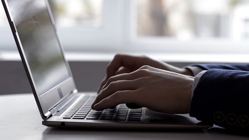 Man Typing on Laptop Keyboard in Office Setting