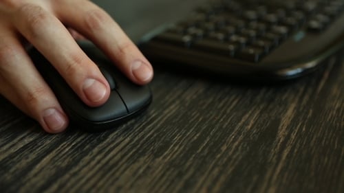 Mano de un hombre trabajando en la computadora haciendo clic en el mouse en el escritorio oscuro