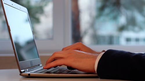 Adult Typing on Laptop in Office Setting