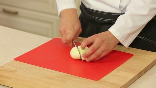 Chef Slicing an Onion on Cutting Board