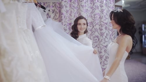 Bridesmaid Helping Friend Choose Perfect Wedding Dress