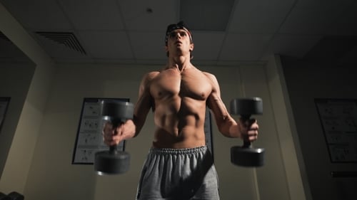 Strong Man, Bodybuilder Exercising With Dumbbells In a Gym